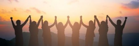 line of employees holding hands in the air and facing the sunset