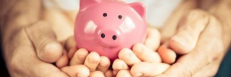 dad holding his kids hands who are holding a pink piggy bank