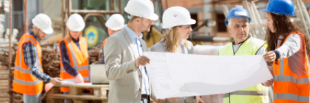 construction site with workers in hard hats reviewing blueprints