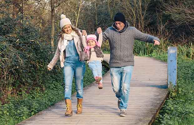 family walking and swinging daughter and having fun because they have free time with debt consolidation