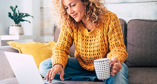 woman on her computer smiling at her savings account