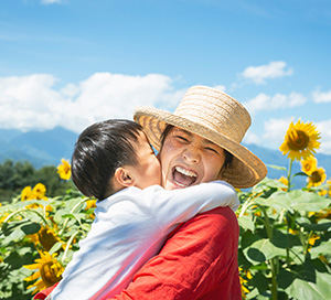 Mom and kid hugging and laughing in sunflower field