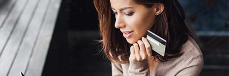 smiling lady using a credit card in a store to make a purchase