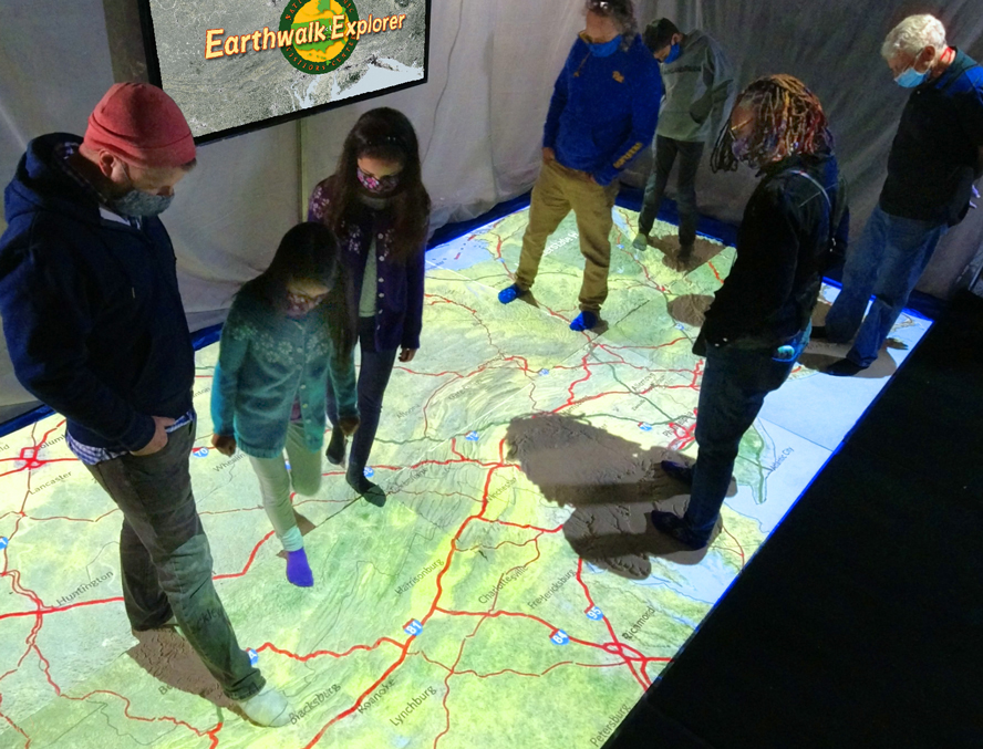 Earthwalk Explorer Exhibit sponsored by 1ST SUMMIT BANK at Heritage Discovery Center with people walking on a lit map