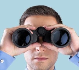 a man in a blue shirt looking through binoculars.