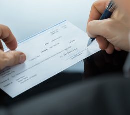 a person holding a pen and writing on a piece of paper.