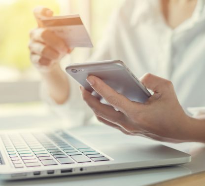 a person holding a credit card while shopping online.