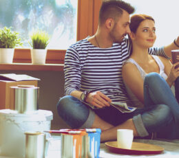 a man and woman sitting on the floor in front of a window.