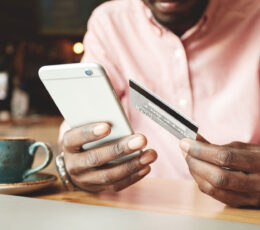 a man sitting at a table holding a smart phone.
