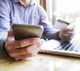 a man holding a credit card while using a laptop.