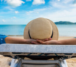 lady in a hat lounging on the beach in a chair