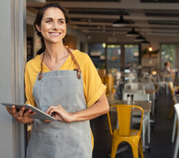 small shop owner at the door on an ipad